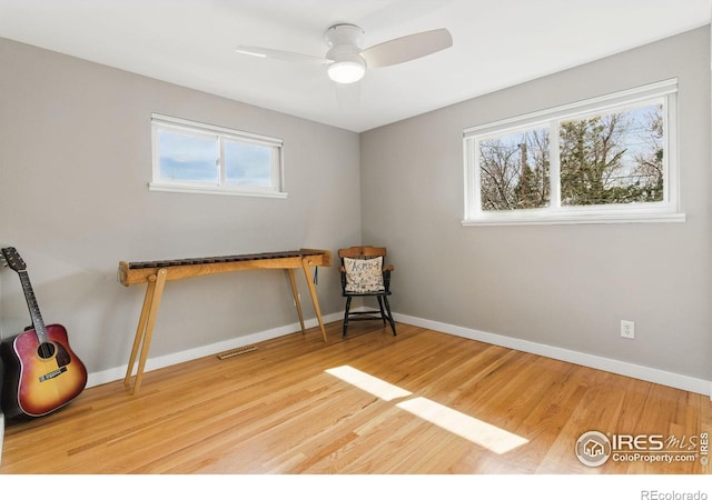 sitting room with a healthy amount of sunlight, visible vents, and wood finished floors