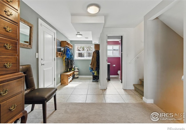 foyer featuring light carpet, stairway, baseboards, and light tile patterned floors