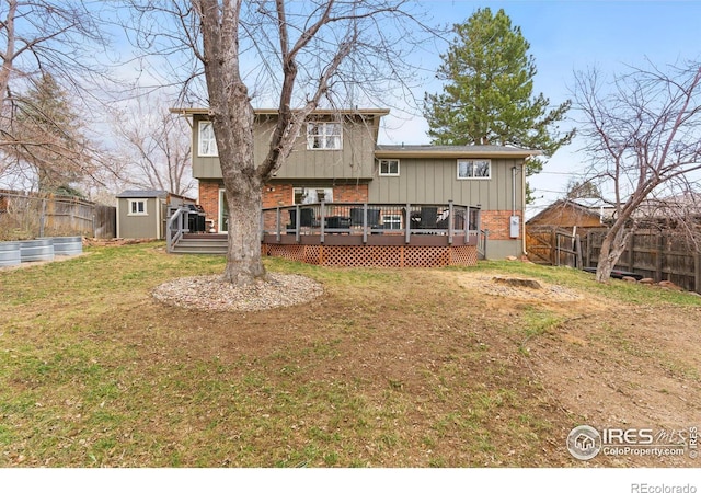 rear view of house featuring brick siding, a lawn, an outdoor structure, and a fenced backyard