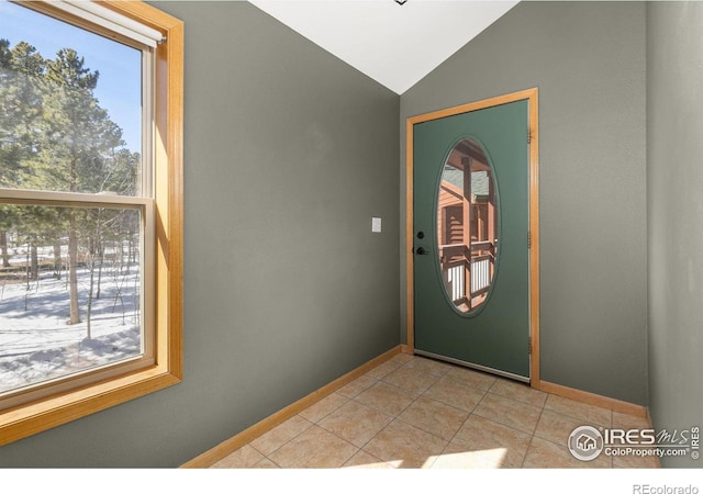 entryway featuring lofted ceiling, baseboards, and light tile patterned floors