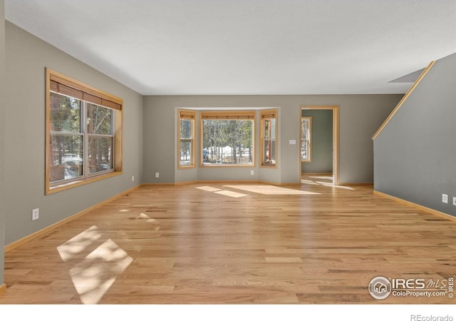 unfurnished living room featuring baseboards and wood finished floors