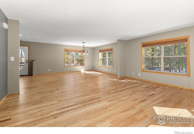 unfurnished room featuring light wood-style floors, baseboards, and a chandelier