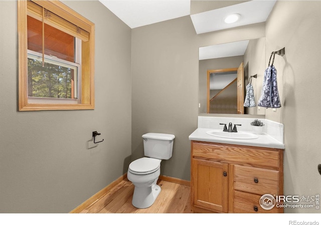 bathroom with baseboards, vanity, toilet, and wood finished floors