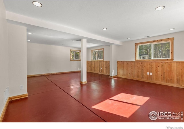 spare room with plenty of natural light, wooden walls, visible vents, and recessed lighting