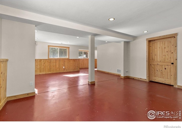 basement with wooden walls, baseboards, visible vents, a wainscoted wall, and recessed lighting