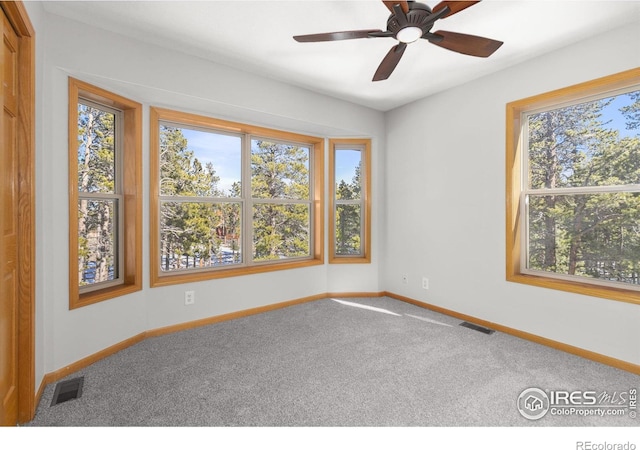 carpeted spare room featuring visible vents, ceiling fan, and baseboards