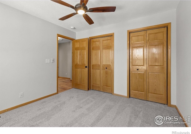 unfurnished bedroom featuring ceiling fan, carpet floors, two closets, and baseboards