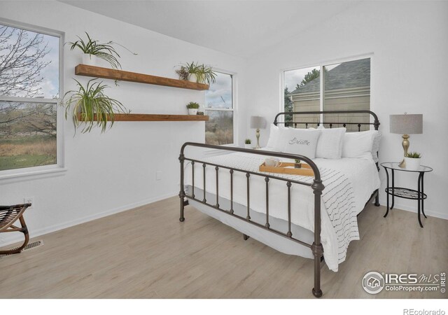 bedroom featuring lofted ceiling, wood finished floors, visible vents, and baseboards