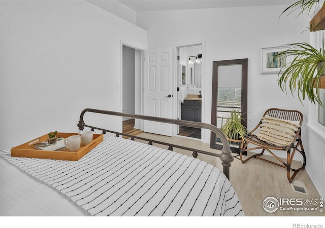 bedroom featuring ensuite bath, baseboards, and wood finished floors