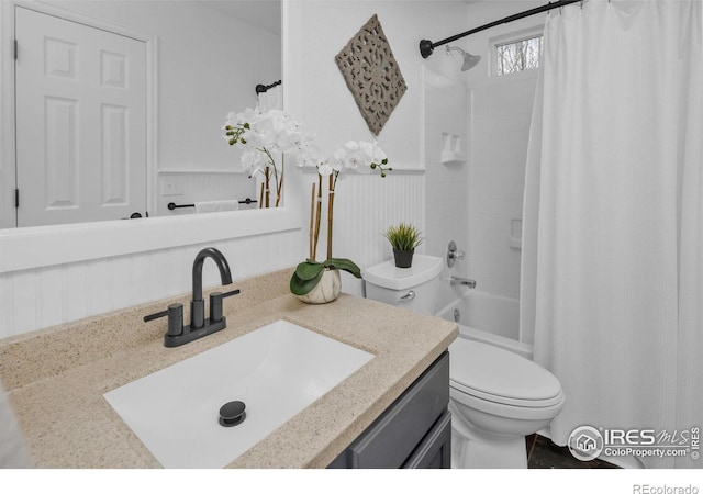 full bathroom featuring toilet, wainscoting, shower / bath combo with shower curtain, and vanity