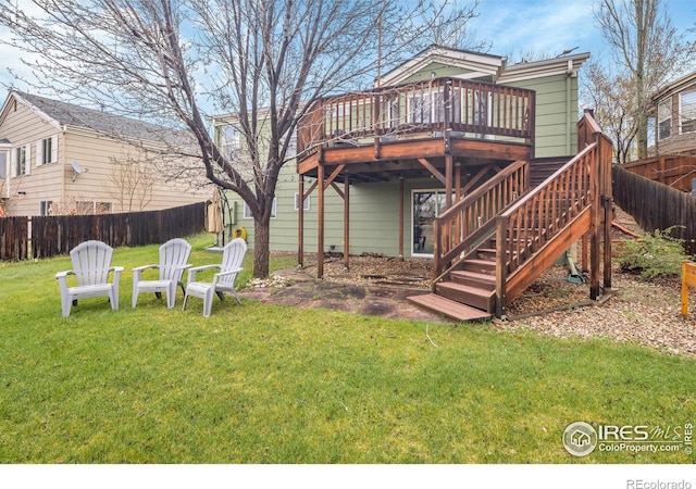 back of house with fence private yard, stairway, a deck, and a lawn