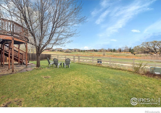 view of yard featuring a rural view, fence, and stairway