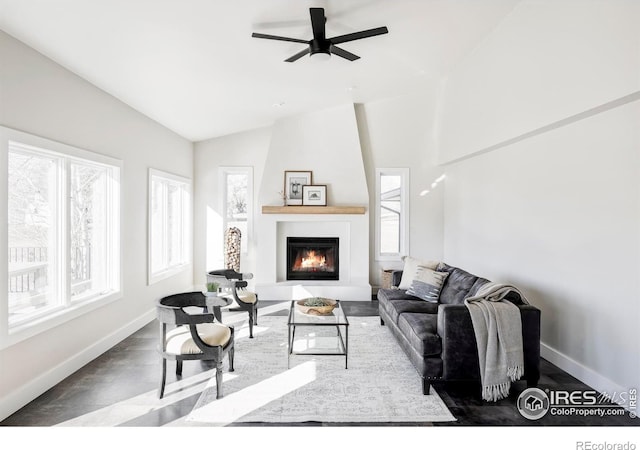 living room featuring vaulted ceiling, ceiling fan, a fireplace, and baseboards