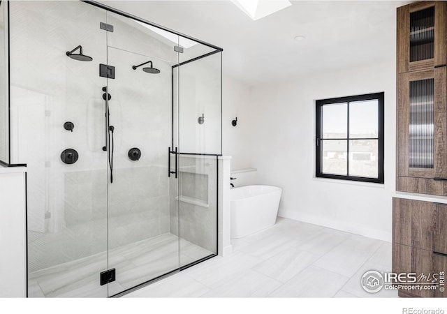 full bath featuring a stall shower, a freestanding tub, and baseboards