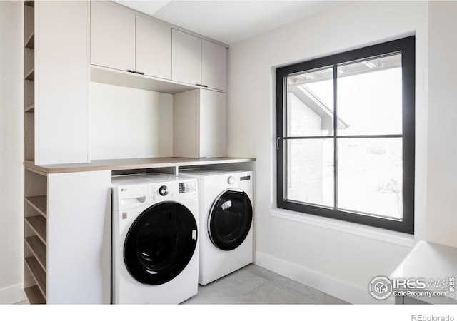 washroom with cabinet space, baseboards, and washer and clothes dryer