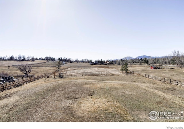 view of yard featuring fence, a mountain view, and a rural view