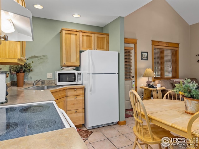 kitchen featuring light tile patterned floors, lofted ceiling, light brown cabinetry, a sink, and white appliances