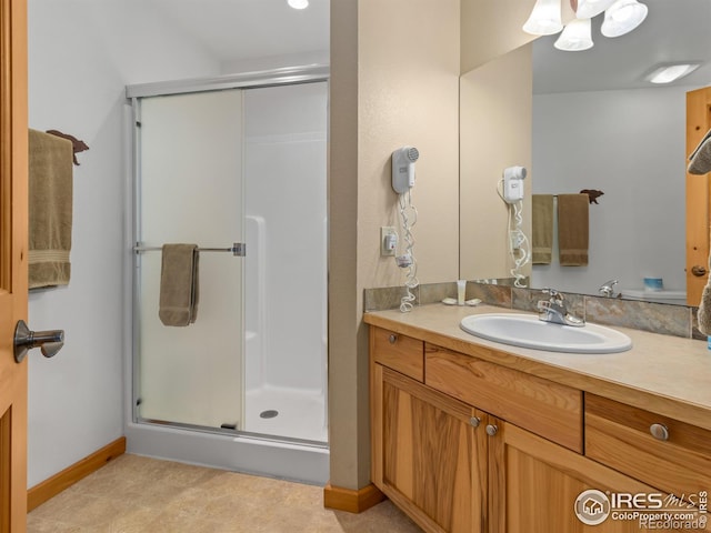 full bathroom with a shower stall, vanity, and baseboards