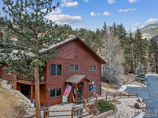 chalet / cabin featuring roof with shingles and fence