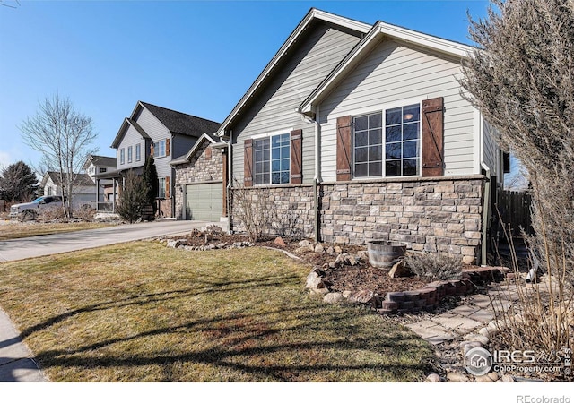 view of side of property with a garage, concrete driveway, a yard, and stone siding