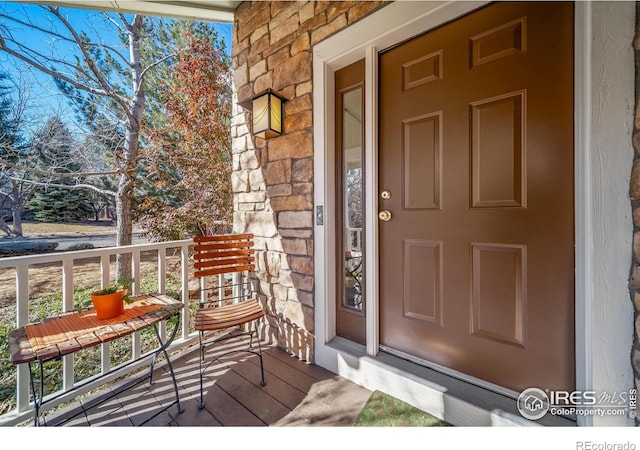 doorway to property featuring a porch and stone siding