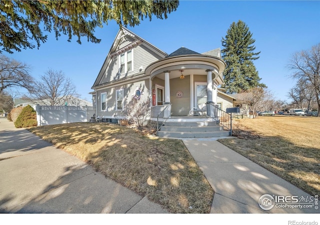 victorian-style house featuring covered porch and a front lawn