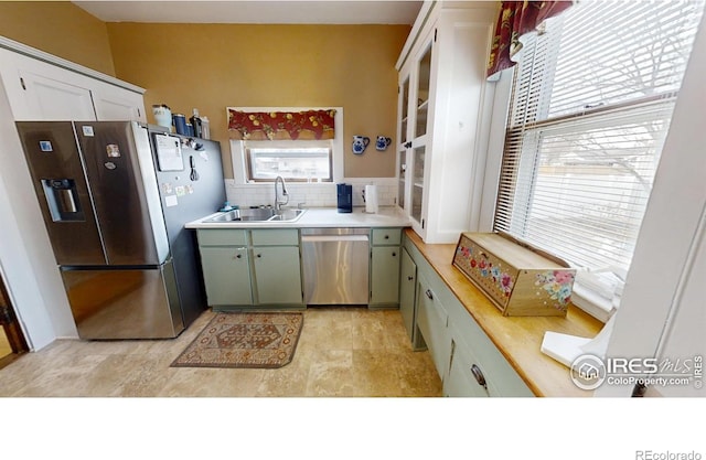 kitchen featuring stainless steel appliances, light countertops, a sink, and backsplash