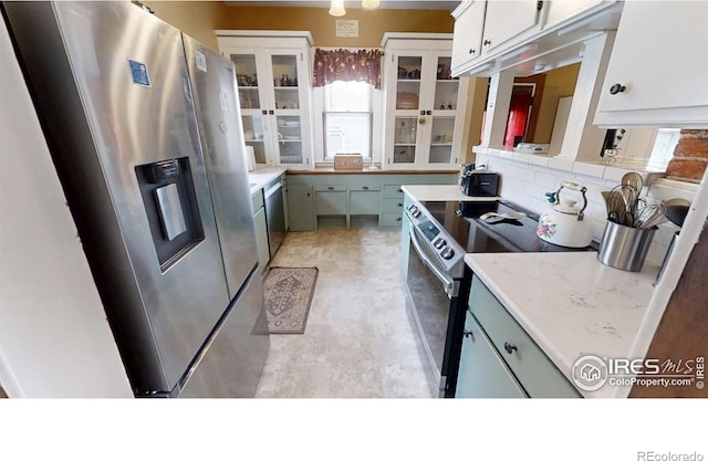 kitchen featuring white cabinetry, light countertops, appliances with stainless steel finishes, tasteful backsplash, and glass insert cabinets