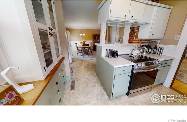 kitchen with under cabinet range hood, visible vents, light countertops, stainless steel electric stove, and tasteful backsplash