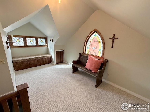 living area with carpet, baseboards, and vaulted ceiling