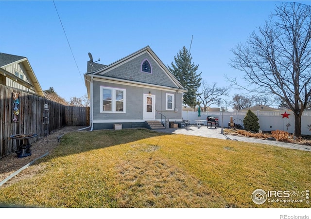 back of house with entry steps, a patio area, a fenced backyard, and a lawn