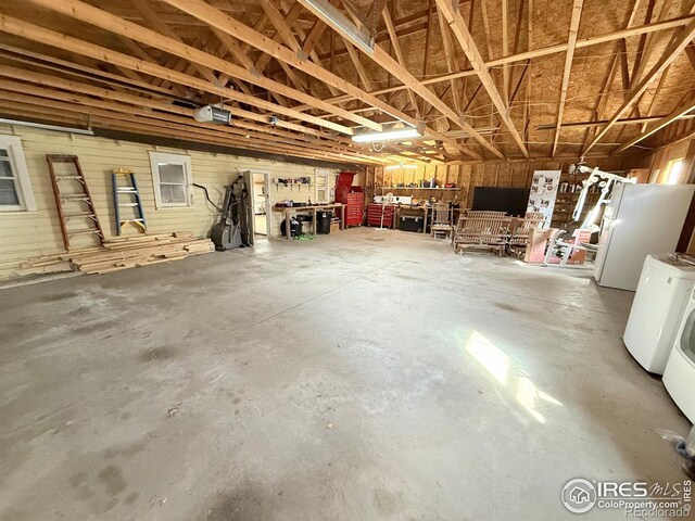 garage with refrigerator, a garage door opener, a workshop area, and freestanding refrigerator