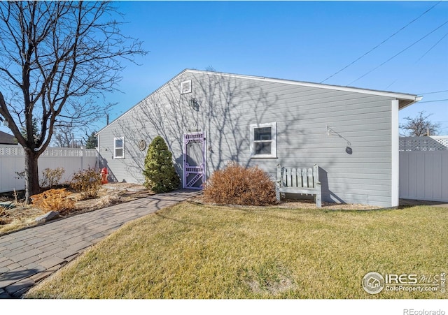 rear view of house with fence and a lawn