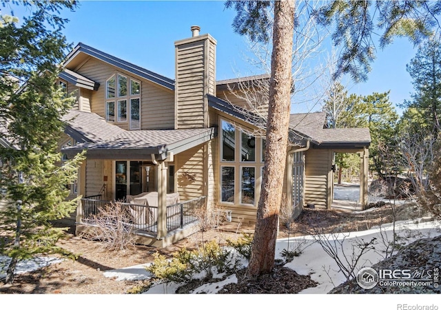 exterior space with a shingled roof and a chimney