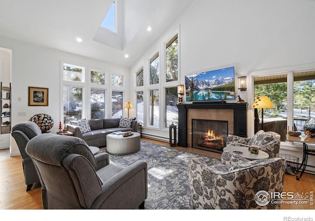 living room featuring a skylight, a fireplace, recessed lighting, wood finished floors, and high vaulted ceiling