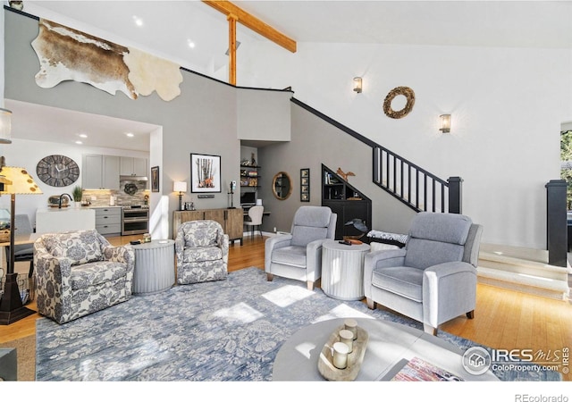 living area with high vaulted ceiling, stairway, beam ceiling, and light wood-style floors