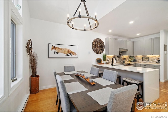 dining area featuring light wood-type flooring, baseboards, a notable chandelier, and recessed lighting