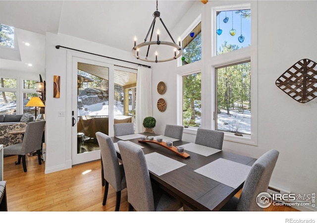 dining space featuring a notable chandelier, a towering ceiling, and light wood finished floors