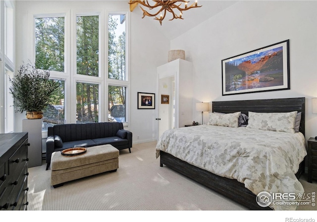 carpeted bedroom featuring baseboards, a high ceiling, and a notable chandelier