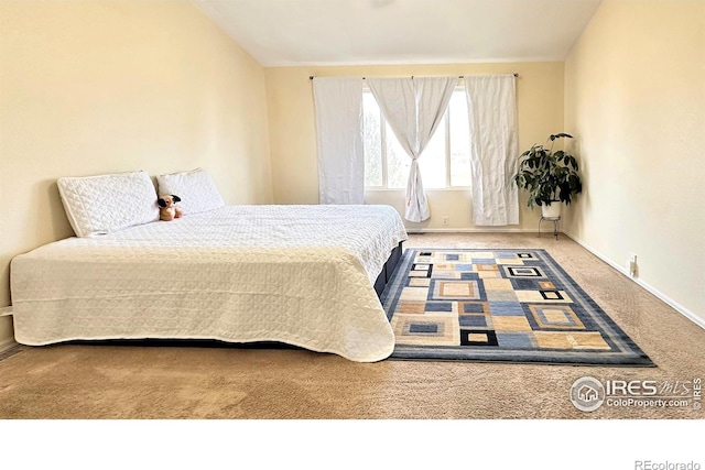 carpeted bedroom with lofted ceiling and baseboards