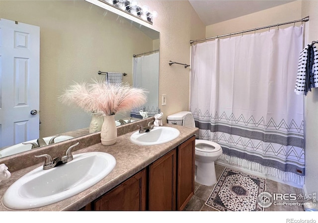 full bath with toilet, curtained shower, double vanity, and a sink