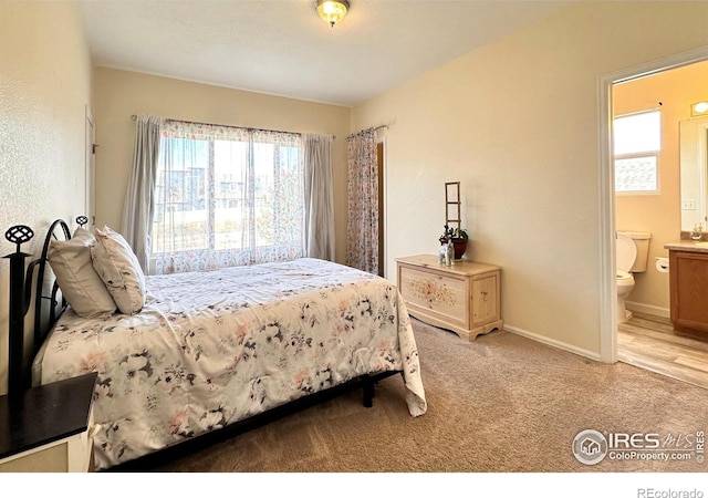 carpeted bedroom with baseboards and ensuite bath