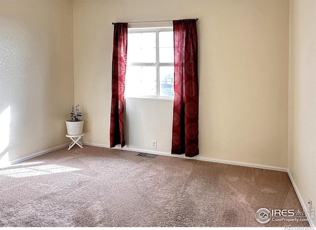 empty room featuring carpet flooring, visible vents, and baseboards