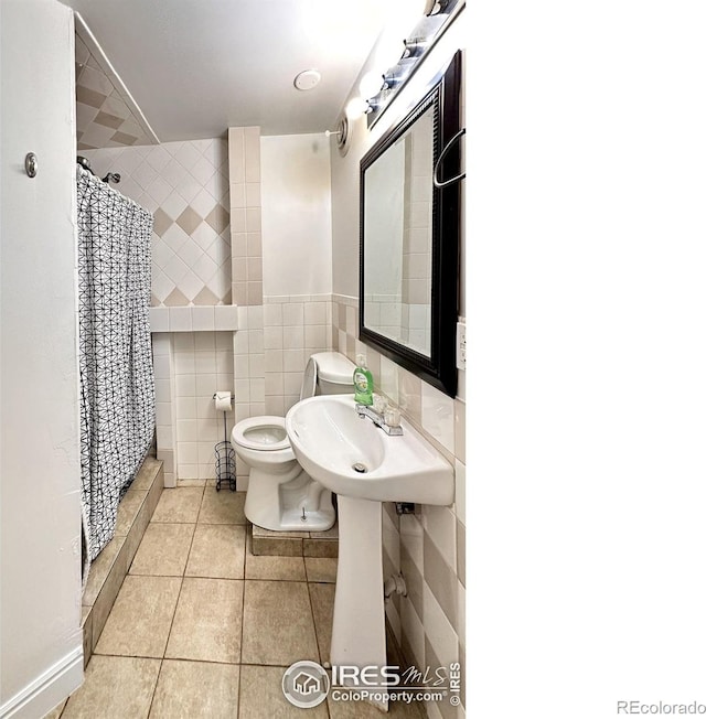 full bath with toilet, curtained shower, tile walls, and tile patterned floors