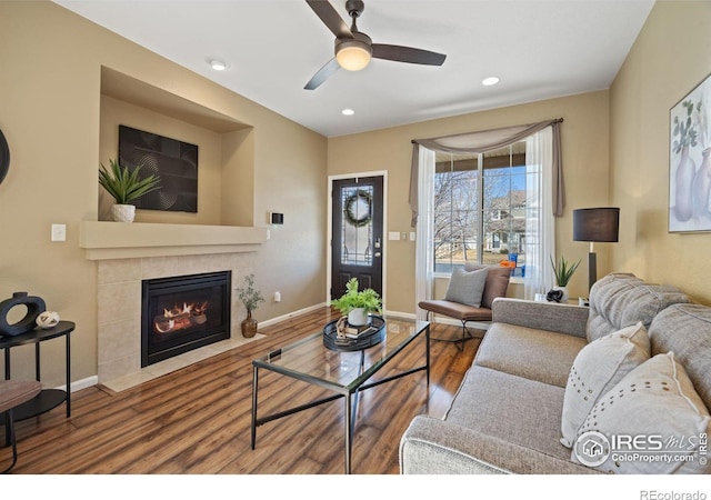 living room featuring wood finished floors, recessed lighting, a tile fireplace, and baseboards