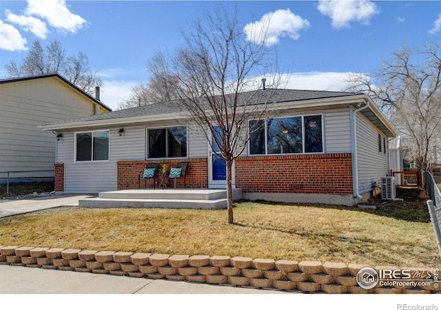 view of front of home featuring driveway, fence, a front lawn, and brick siding