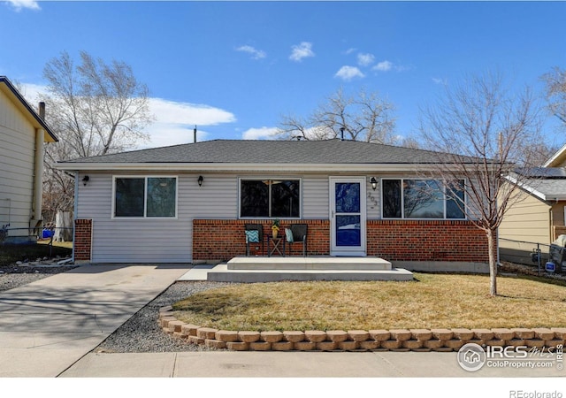 ranch-style home with a front yard, concrete driveway, and brick siding