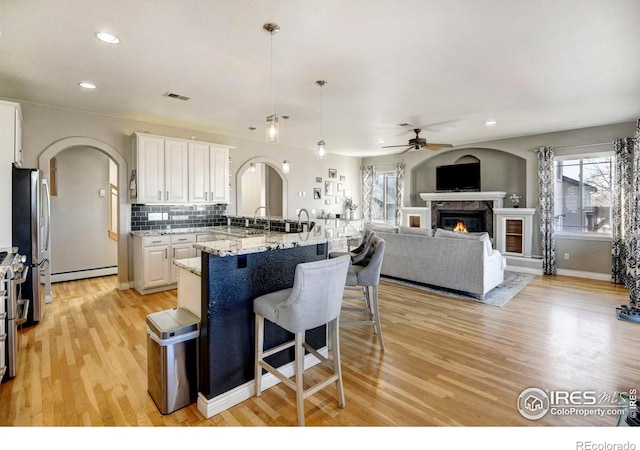 kitchen with white cabinets, arched walkways, a breakfast bar, and a glass covered fireplace