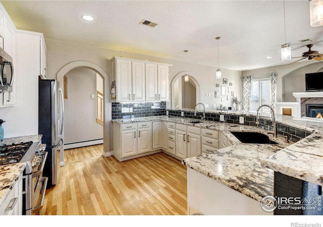 kitchen with arched walkways, stainless steel appliances, visible vents, open floor plan, and a sink