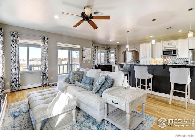 living area featuring recessed lighting, visible vents, light wood-style flooring, a ceiling fan, and baseboards